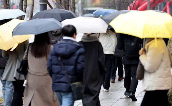 People hold umbrellas under the rain on Monday. [NEWS1]