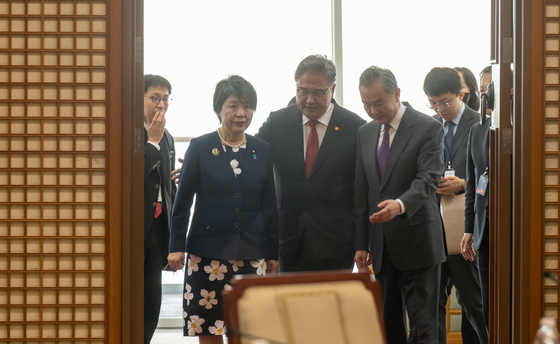 From left, Japanese Foreign Minister Yoko Kamikawa, South Korean Foreign Minister Park Jin and Chinese Foreign Minister Wang Yi enters a meeting room at Nurimaru APEC House in Haeundae, Busan, on Sunday. [JOINT PRESS CORPS]