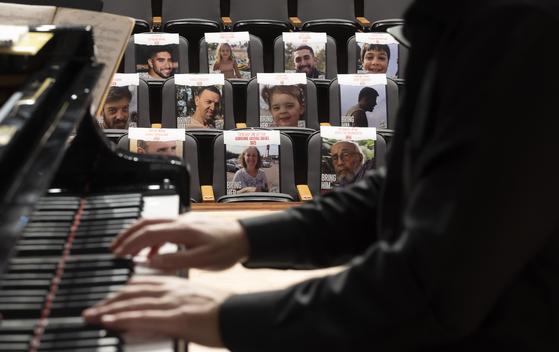 A pianist rehearses at Seoul National University's concert hall in Seoul during a recital on Nov. 1 in front of seats filled with pictures of the 240 people believed to have been taken hostage during an attack by the militant group Hamas on Israel on Oct. 7. The Israel Embassy in Seoul hosted the “Concert of the Missing” to stand in solidarity with the hostages and their families and to demand the immediate and unconditional release of all hostages. [YONHAP]