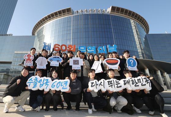 Employees from the Korea International Trade Association (KITA) pose for a photo a day ahead of the 60th anniversary of Trade Day, which falls on Dec. 5, in front of the Starfield COEX Mall in Gangnam District, southern Seoul. The Styrofoam signs they hold show Korea's major exports in chronological order, from squid in the 1960s up to Korean food in the 2010s, as well as automobiles and semiconductors in between. [YONHAP]