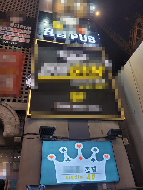 Signs of Hold’ em pubs are lit up in Suwon, Gyeonggi. Hold ’em pubs occupy three of the building's eight stories. The banner says the pub offers free beer and drinks and teaches Hold ’em rules without any fee. However, upon entry, players must pay at least 50,000 won to earn 10 chips to play the game. [SON SUNG-BAE, JOONGANG PHOTO]