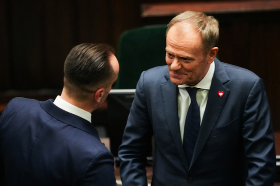 Newly appointed Polish Prime Minister Donald Tusk, pictured right, talks with Polish MP Janusz Kowalski of Sovereign Poland during a parliamentary session break in Warsaw on Tuesday. [REUTERS/YONHAP]