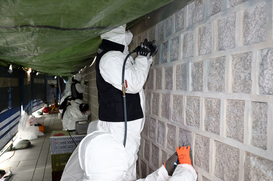 Cultural Heritage Administration officials working on the restoration of the walls of Gyeongbok Palace that were vandalized over the weekend. [YONHAP] 