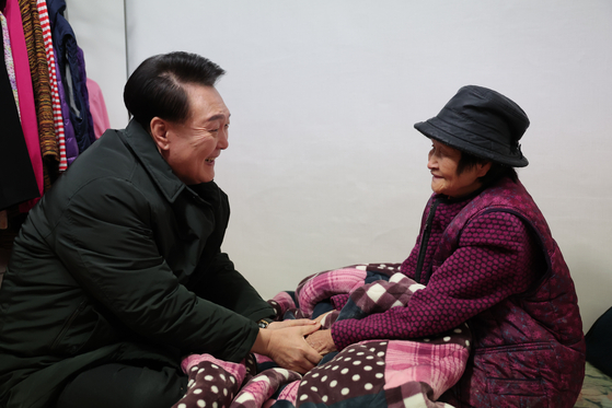 President Yoon Suk Yeol, left, speaks with a senior citizen who lives alone in a multiunit house in Jungnang District, eastern Seoul, on Thursday, to provide winter supplies amid freezing temperatures this week. [PRESIDENTIAL OFFICE]