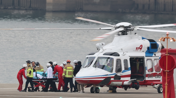 Democratic Party leader Lee Jae-myung disembarked from the helicopter that arrived from Busan upon landing at the pad on Nodeul Island in Yongsan, Seoul, on Tuesday. Lee was transferred to the Seoul National University Hospital after he was attacked. [YONHAP] 