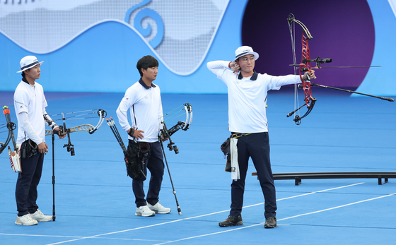 Korean archer Kim Jong-ho, right, competes in the compound men's team gold medal match against India at Fuyang Yinhu Sports Centre Final Field in Hangzhou, China on Thursday. [YONHAP]