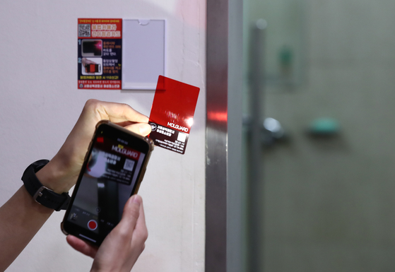 A Korean police officer surveying for hidden camera at a public toilet at a university in Seoul in 2020. Photo is unrelated to the story. [YONHAP]