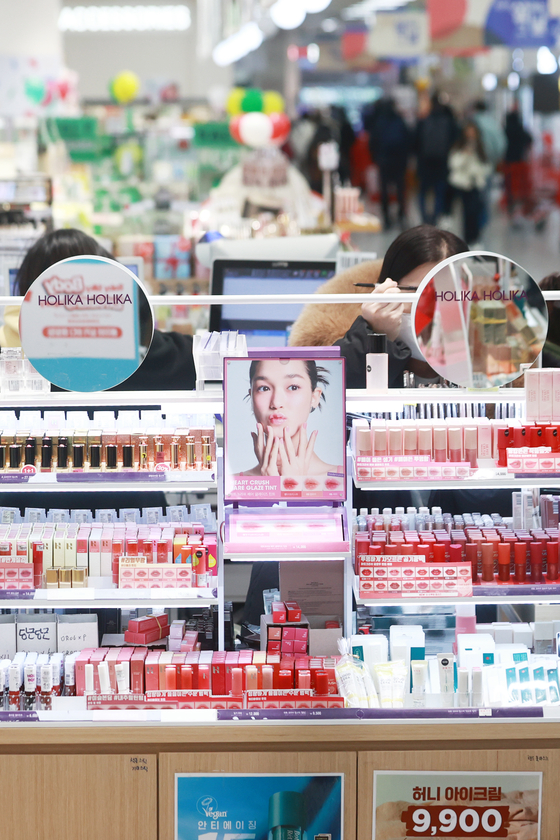 Customers try cosmetics products at a mall in downtown Seoul on Sunday. Exports of light industry products accounted for 29.8 percent of Korea's total exports last year, largely driven by the boosted exports of Korean cosmetics, according to data from Korea International Trade Association. [YONHAP] 