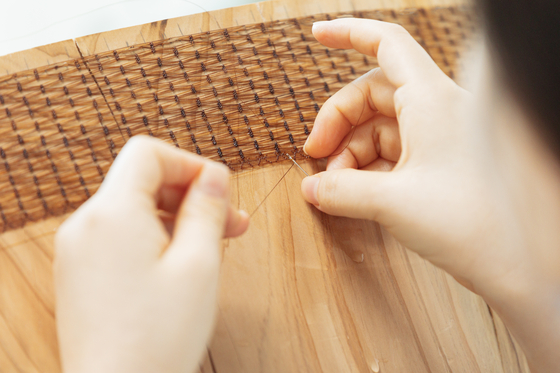 Jeong Da-hye works on her horsehair baskets at her studio inside her home in Seoul. [SOLUNA CRAFT]