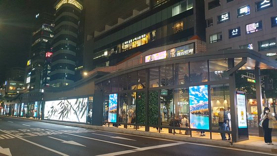 Digital signage installed at a bus stop near Hongik University in western Seoul displays advertisements. [JOONGANG ILBO]