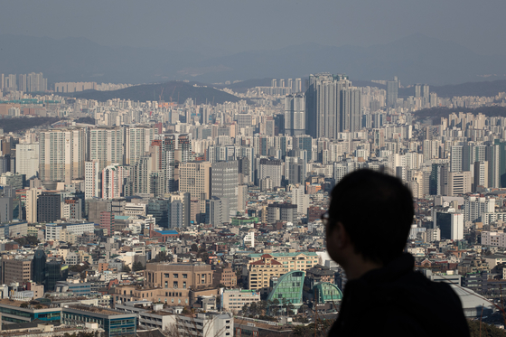 A pedestrian looks at apartment buildings from Mount Namsan in central Seoul on Sunday. [NEWS1] 