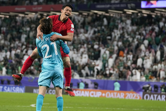 Korea's Hwang Hee-chan, right, celebrates with goalkeeper Jo Hyeon-woo after scoring the winning penalty in a penalty shootout at the end of the Asian Cup round of 16 match between Saudi Arabia and Korea at the Education City Stadium in Qatar on Tuesday.  [AP/YONHAP]