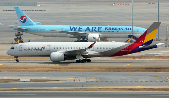 An Asiana Airlines aircraft taxis past a Korean Air plane on the runway at Incheon International Airport on Tuesday. [NEWS1]