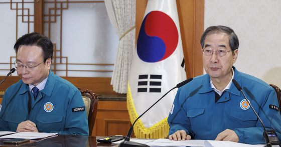 Prime Minister Han Duck-soo, right, speaks in a meeting held in response to the anticipated mass strike by doctors, along with related ministries, at the government complex in downtown Seoul on Monday. [YONHAP] 