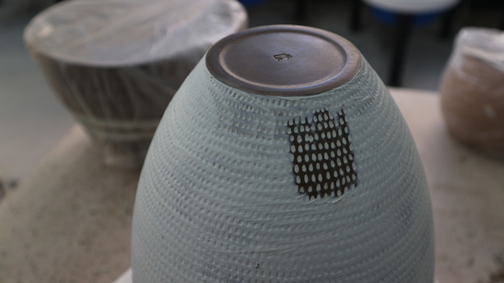 Pigmented clay, shown in blue here, covers the dark stoneware via countless dots in Yoon Jung's ceramics. [YOON JUNG]