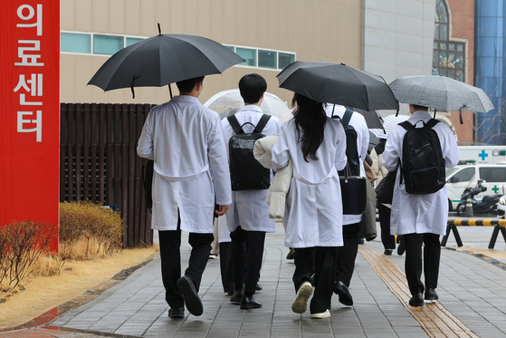 A group of medical professionals walk near a hospital in Seoul on Monday. Medical chaos is anticipated in Korea as trainee doctors at five major hospitals were set to submit their resignation letters by Monday to protest the government's decision to increase the enrollment quota at medical schools. [YONHAP] 