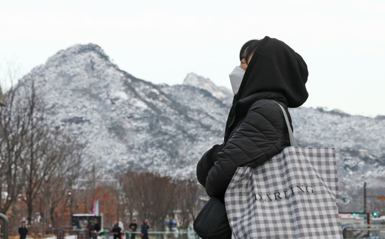 A passerby walks outside in the cold weather in Jongno District, downtown Seoul, on Friday. Snow and rain fell across the peninsula the day before, with Seoul seeing 13 centimeters (5 inches) of snow Thursday morning. [NEWS1] 