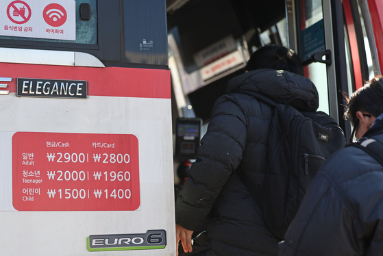 Passengers board a bus near Seoul Station on Monday as public service costs rise, despite the government's attempt to freeze such fees.[YONHAP]