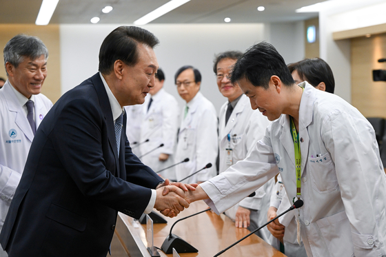President Yoon Suk Yeol shakes hands with a doctor at Asan Medical Center in southern Seoul on Monday before meeting with medical professionals and the hospital director on the same day. Yoon's visit marks the first time that he has visited a hospital since the announcement of the medical school admissions quota increase last month. [PRESIDENTIAL OFFICE]