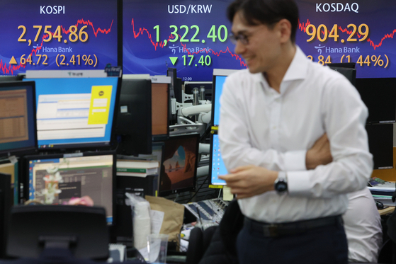 Electronic signboards at a Hana bank branch in Seoul show the benchmark Kospi surged 64.72 points, or 2.41 percent, to close at 2,754.86, while the value of local currency also rose sharply against the U.S. dollar to finish at 1,322.40 won against the greenback on March 21, 2024.