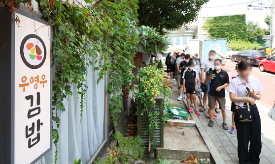 People queue to eat gimbap (Korean seaweed rolls) at an eatery that was showcased in the hit Korean series "Extraordinary Attorney Woo" in the summer of 2022. [NEWS1]