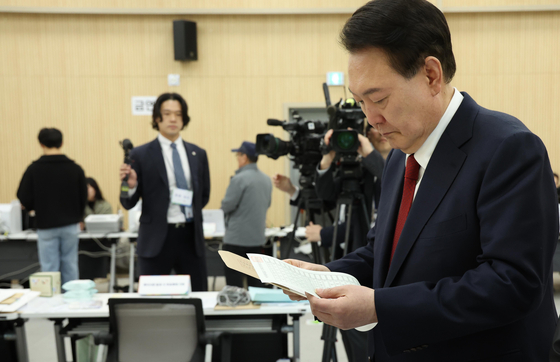 President Yoon Suk Yeol checks his ballot paper at a welfare center in Busan Friday, as Korea began its two-day early voting for next week's general election. [JOINT PRESS CORPS]