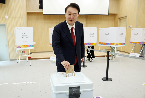 President Yoon Suk Yeol drops his vote into the ballot box at a polling station at a welfare center in Gangseo District, Busan, Friday, as Korea began its two-day early voting for next week's general election. [JOINT PRESS CORPS]