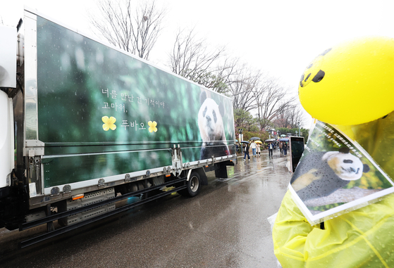 A vehicle carrying Fu Bao passes by the crowd, wrapped with her image and a phrase saying "It's a miracle meeting you." [JOINT PRESS CORPS]