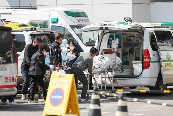 Paramedics and caretakers transfer patients to an emergency room at a general hospital in Seoul on Monday. [NEWS1]