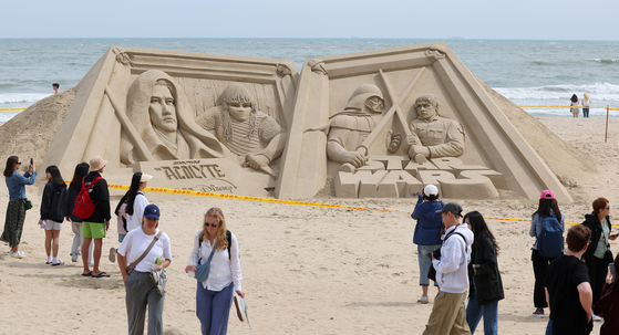 Visitors take pictures of a Star Wars-themed sand sculpture at Haeundae Beach in Busan on Monday, the last day of the three-day Children’s Day holiday. [YONHAP]
