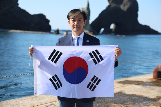 Cho Kuk, the leader of the liberal Rebuilding Korea Party, holds the Korean national flag as he visits the Dokdo islets on Monday. [REBUILDING KOREA PARTY] 