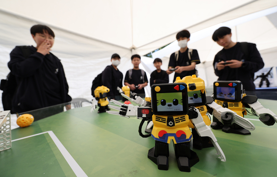 Players control humanoid robots with cat faces in a football game at the Y Education Fair, held at Yangcheon Park, western Seoul, on Thursday. [YONHAP]