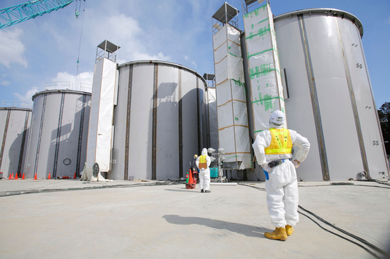 A worker wearing a protective suit and a mask looks up at storage tanks for radioactive water, under construction in the J1 area at the Tokyo Electric Power Company's (Tepco) tsunami-crippled Fukushima Daiichi nuclear power plant in Okuma, Fukushima prefecture in this file photo. [AFP/YONHAP]
