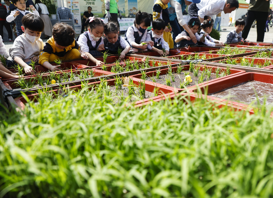 Children have a rice-planting experiece during the19th Busan Urban Agriculture Expo 2023 held at Busan Citizens Park in Busanjin District, Busan, on Thursday. The farm exhibition runs through Sunday. [YONHAP]