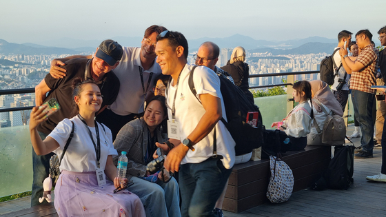 A group of tourists take photos together at the N Seoul Tower in central Seoul's Namsan on May 23 as part of a tour event dubbed “KOREA invites U,” hosted by the Ministry of Culture, Sports and Tourism in collaboration with the Korea Tourism Organization. [YOON SO-YEON]