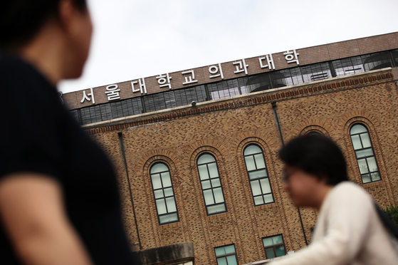 Two people walk in front of the building of the School of Medicine of Seoul National University in central Seoul on Thursday, a day when the Education Ministry confirmed a medical recruitment expansion. [NEWS1]