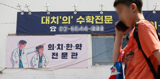Students pass by a light pink colored banner advertising a cram school's preparatory program for medical school admissions in Daechi-dong, Gangnam District, in southern Seoul on May 17. [YONHAP] 