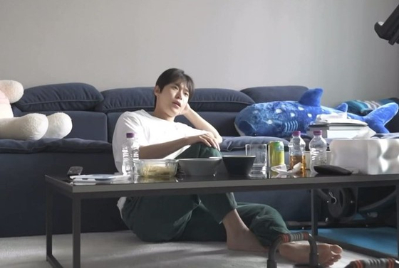 Boy band NCT's Doyoung leans against his sofa during an episode of MBC's ″I Live Alone″ (2013-). [SCREEN CAPTURE]