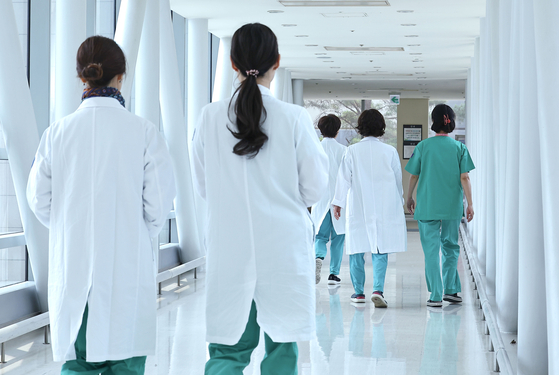 Doctors walk at a hospital in Seoul on Monday, a day after the Korean Medical Association announced a general strike on June 18 to protest the government's decision to increase the medical school quota. [YONHAP] 
