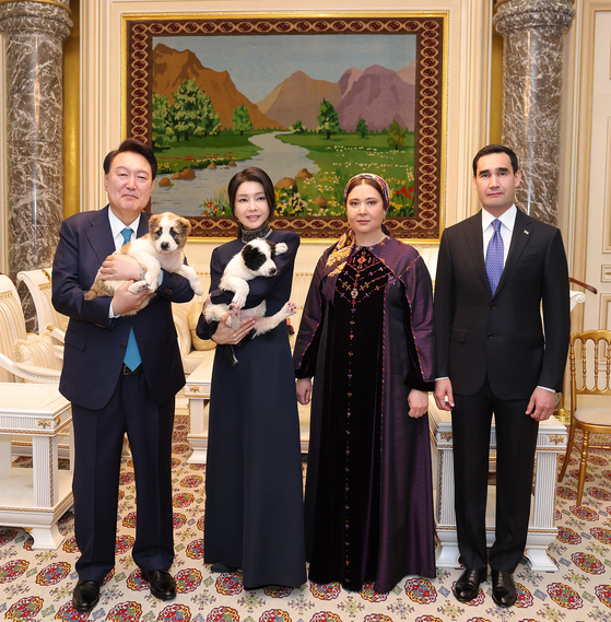 Korean President Yoon Suk Yeol, left, and first lady Kim Keon Hee, hold Turkmenistan’s national dog breed, a Central Asian shepherd known as the Alabai, in a commemorative photograph with Turkmen President Serdar Berdimuhamedov, right, and his wife at a state banquet held at a hotel in Ashgabat on Monday. [JOINT PRESS CORPS]