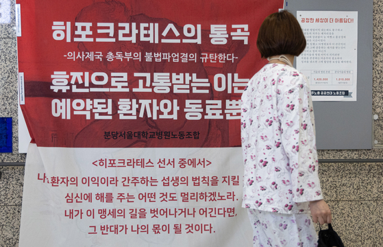 A patient reads a poster criticizing striking doctors for harming patients and burdening other health workers at Seoul National University Bundang Hospital in Gyeonggi on Sunday. [NEWS1]