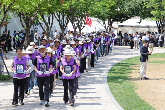 Members of groups representing bereaved families of victims of the Itaewon crowd crush of Oct. 29, 2022, march down a street in central Seoul on Sunday as they move the site of a memorial altar for the tragedy, which claimed 159 lives. The memorial for the Itaewon victims was relocated to the Burim Building in central Seoul after standing on Seoul Plaza for 16 months. [YONHAP]