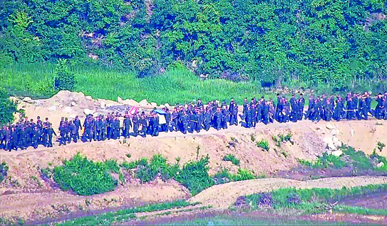  North Korean soldiers work somewhere along the border in the demilitarized zone in a photo provided by the South’s Joint Chiefs of Staff Tuesday. [JOINT CHIEFS OF STAFF]