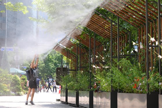 A person enjoys mist from a fogging system at Seoul City Hall on Thursday. [NEWS1]