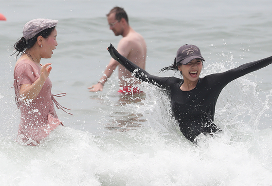 People play in the water at Haeundae Beach in Busan, where the temperature reached 33 degrees Celsius (91.4 degrees Fahrenheit) on Wednesday. [NEWS1] 
