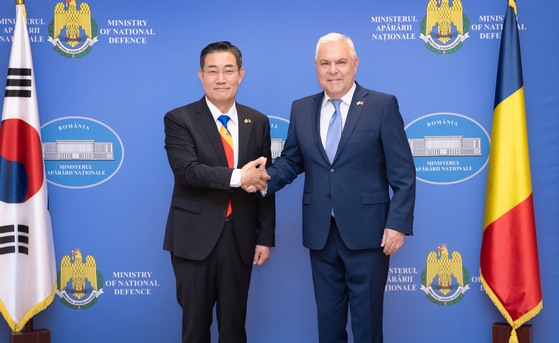 Defense Minister Shin Won-sik, left, and his Romanian counterpart, Angel Tilvar, shake hands during their meeting in Romania on Wednesday. [YONHAP]