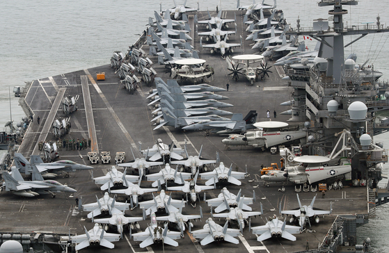 The Nimitz-class nuclear-powered aircraft carrier USS Theodore Roosevelt, right, departs Busan on Wednesday to take part in Freedom Edge, a new trilateral multi-domain exercise involving South Korea, the United States and Japan, in waters off the peninsula's southern coast. [NEWS1] 
