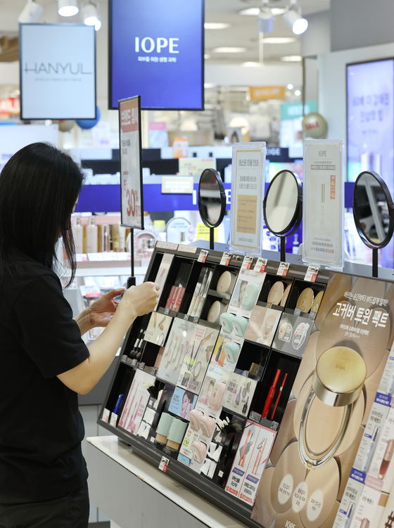 A customer tries out beauty products at a cosmetics display aisle in a Seoul supermarket on Thursday. [YONHAP]