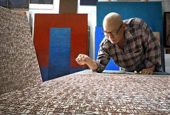 Artist Shin Yong-il works on his artwork featuring texts from “Jikji Simche Yojeol,” which roughly translates to "Anthology of Great Buddhist Priests’ Zen Teachings," at his studio in Gunpo, Gyeonggi. [PARK SANG-MOON] 