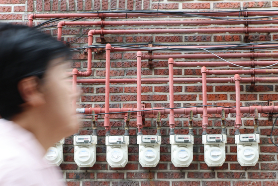 A pedestrian walks past gas meters installed on a wall at a building in Seoul on Friday. [YONHAP]